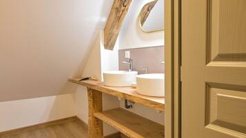 A bathroom with a wooden vanity, two white sinks, and a mirror.