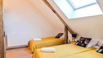 Una habitación con dos camas, un tragaluz, vigas de madera y un radiador.