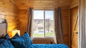 A wooden cabin room with a bed, a nightstand, and a window with curtains. - The Ridge Cabin! 15-minutes from the ARK (Williamstown)