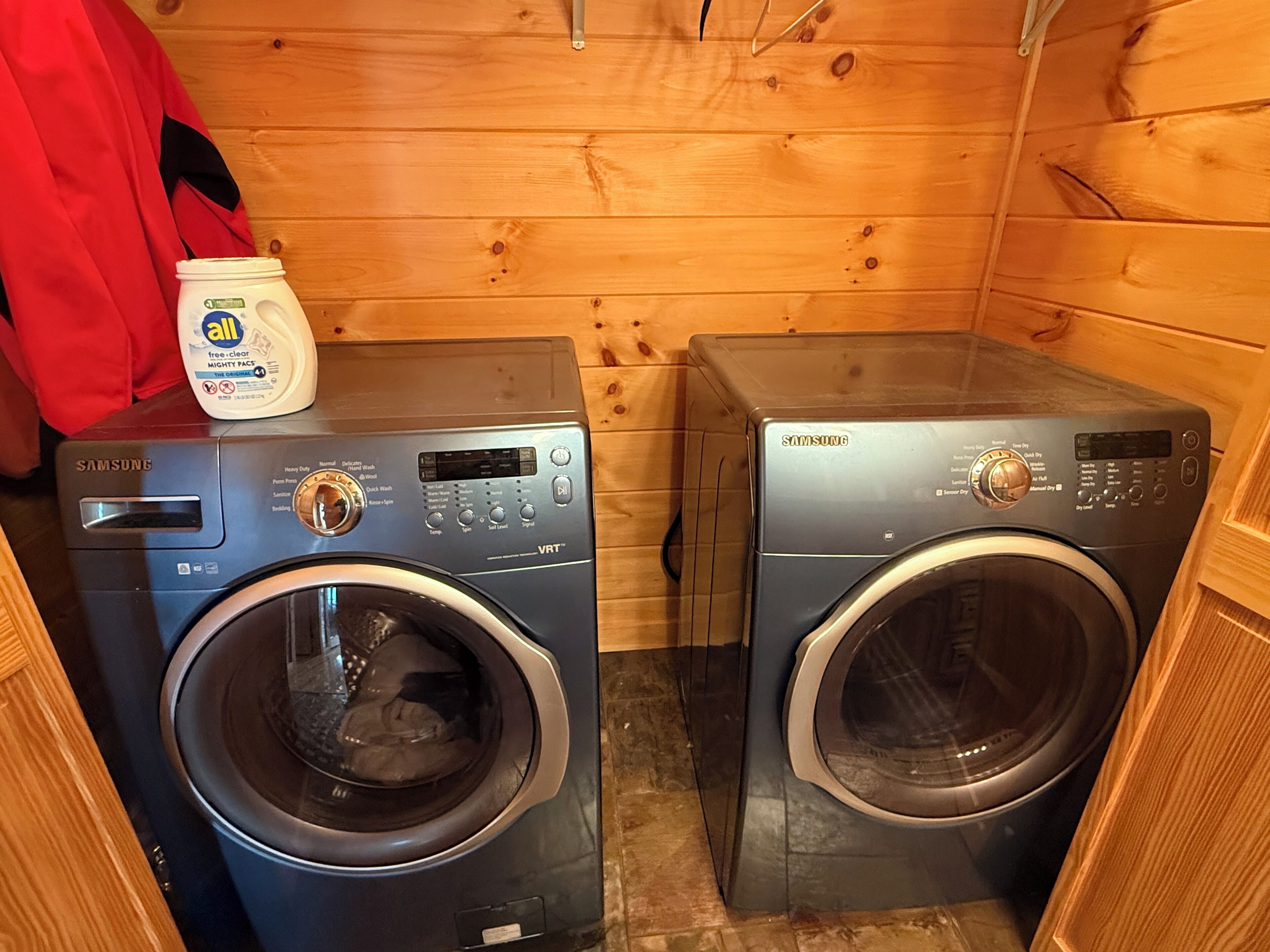 Two Samsung VRT front-loading washing machines in a wooden-walled laundry room.