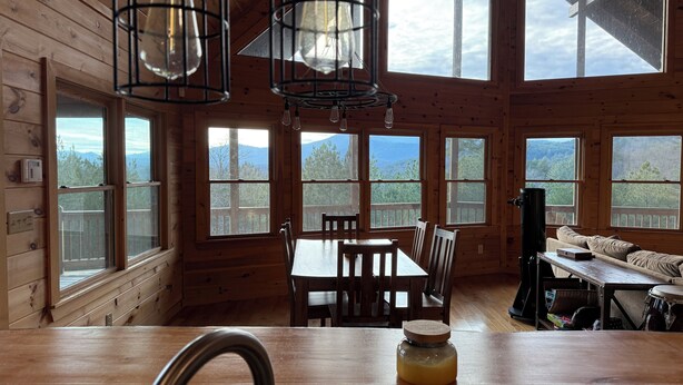 A wooden cabin with large windows, a dining area, and a kitchen counter. - Gorgeous Cabin Private Retreat on 15 acres (Copperhill)
