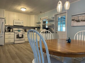 Kitchen with oven, microwave, and stove, plus dining area with wooden table and chairs.