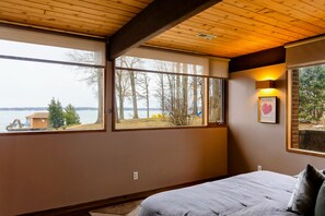This bedroom boasts expansive windows, offering serene views of the lake and surrounding nature, creating a tranquil retreat. - Lakefront Lake Anna Views, Dock, Hot Tub, Firepit (Bumpass)