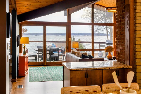 The Great Room seamlessly connects indoor elegance with outdoor charm, offering breathtaking views of the lake through expansive windows that lead directly to the spacious deck, perfect for dining or lounging by the water. - Lakefront Lake Anna Views, Dock, Hot Tub, Firepit (Bumpass)