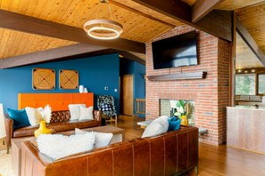 The Great Room features a warm and inviting design with a vaulted wooden ceiling, plush leather seating, and a central brick fireplace topped with a flat-screen TV, creating the perfect space for relaxation and entertainment. - Lakefront Lake Anna Views, Dock, Hot Tub, Firepit (Bumpass)