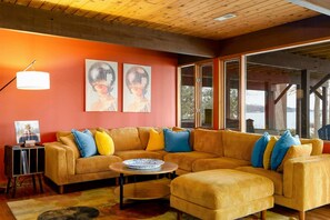 A modern living room with a large sectional sofa, a coffee table, and artwork on the wall. - Lakefront Lake Anna Views, Dock, Hot Tub, Firepit (Bumpass)