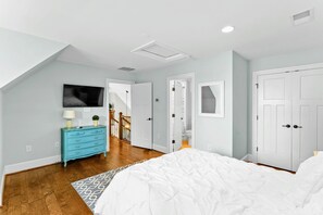 A bedroom with a bed, a dresser, a television, and a door leading to another room. - Lakefront Lake Anna 5 Suites, Dock, Beach (Mineral)