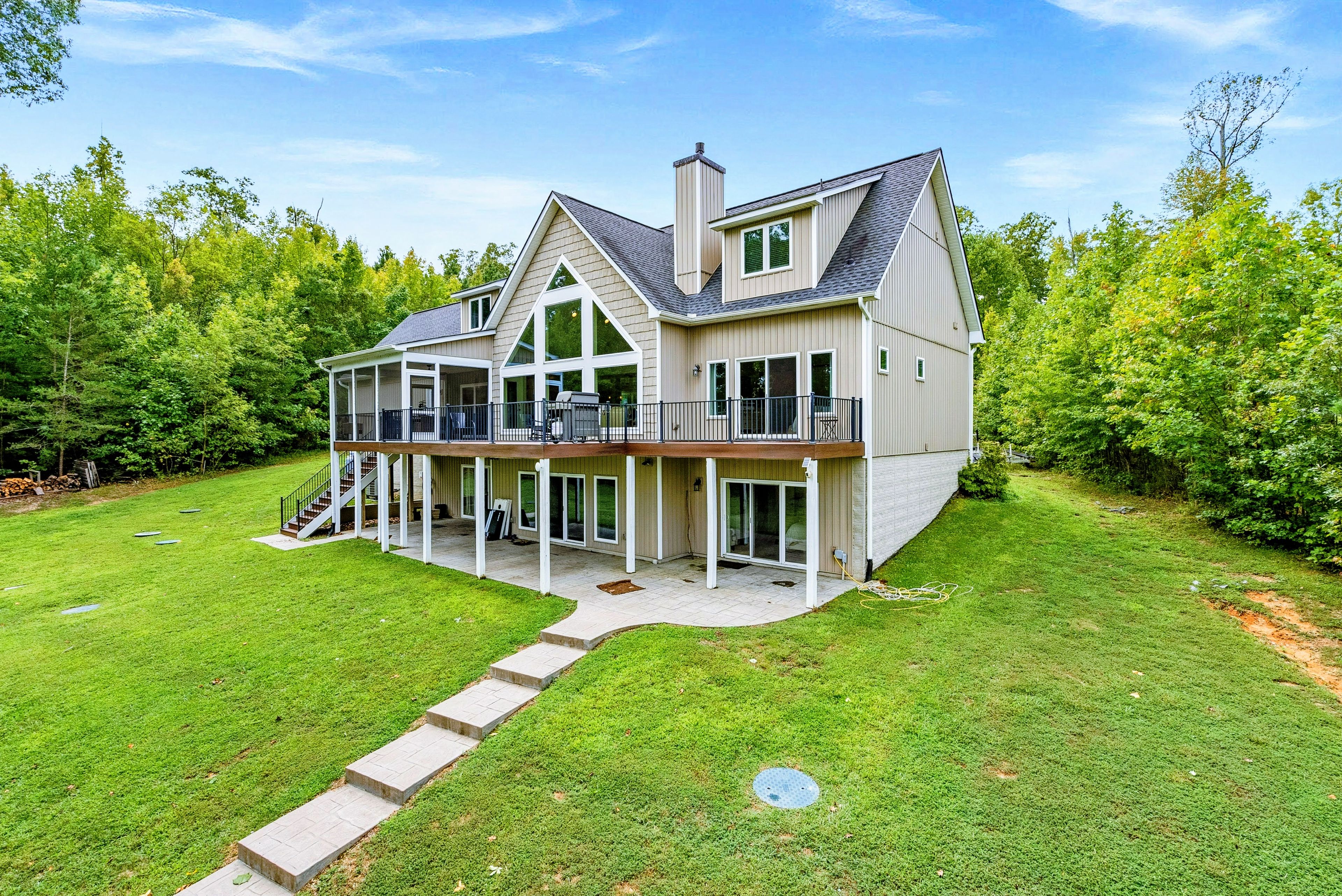 Une maison à deux étages dotée d’une grande terrasse, d’un porche couvert et d’une pelouse bien entretenue.