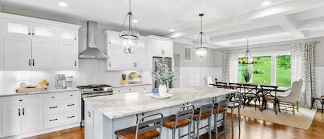 A modern kitchen with white cabinetry, a large island with bar stools, and pendant lighting.