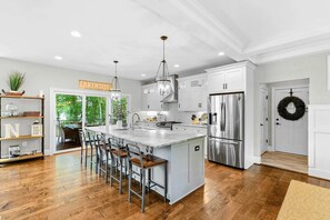 A spacious kitchen with a large island, stainless steel appliances, and a view to the outdoors.