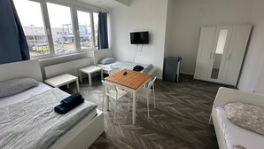 A modern hotel room with a bed, a small table, a TV, and a wardrobe. - Akdeniz Pension (Ludwigsfelde)