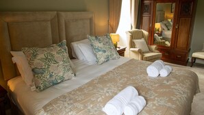 A well-appointed hotel room with a large bed, floral-patterned bedding, a wooden wardrobe, and a sitting chair. - Hill House – Luxury Group Getaway with Stunning Views, Sleeps 17 (Cashel)