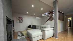 A modern living room with a sectional sofa, a fireplace, and a staircase. - Large private bungalow in Lévis (Saint-Nicolas)