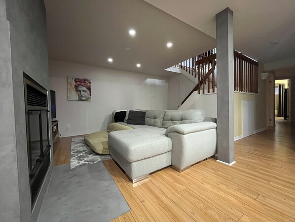 A modern living room with a sectional sofa, a fireplace, and a staircase.