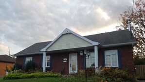 A single-story house with a brick facade, white trim, and a number '224' sign on the door. - Large private bungalow in Lévis (Saint-Nicolas)
