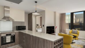 A modern kitchen with a built-in microwave, a stainless steel range hood, and a marble countertop. - Designer One Bed Apt | No Loadshedding (Cape Town)