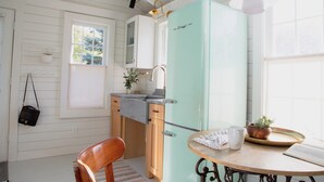 A kitchen with a vintage teal refrigerator, wooden cabinets, a small sink, and a dining table with a plant and a mug. - New listing! Cozy, fresh and clean 1-bedroom cottage with Pond access in Chatham (Chatham)