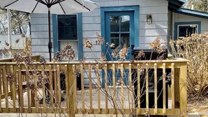 A house with a blue door and windows, a deck with a railing, and a patio umbrella. - New listing! Cozy, fresh and clean 1-bedroom cottage with Pond access in Chatham (Chatham)