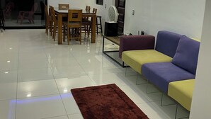 Un salon moderne comprenant un coin repas, un canapé, un ventilateur et un tapis marron.