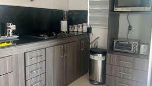 Une cuisine moderne avec des meubles gris, une poubelle en acier inoxydable, un four à micro-ondes et un grille-pain.