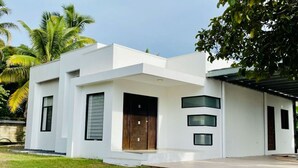 Une maison moderne à deux étages, dotée d’un toit plat, de grandes fenêtres et d’une porte en bois.