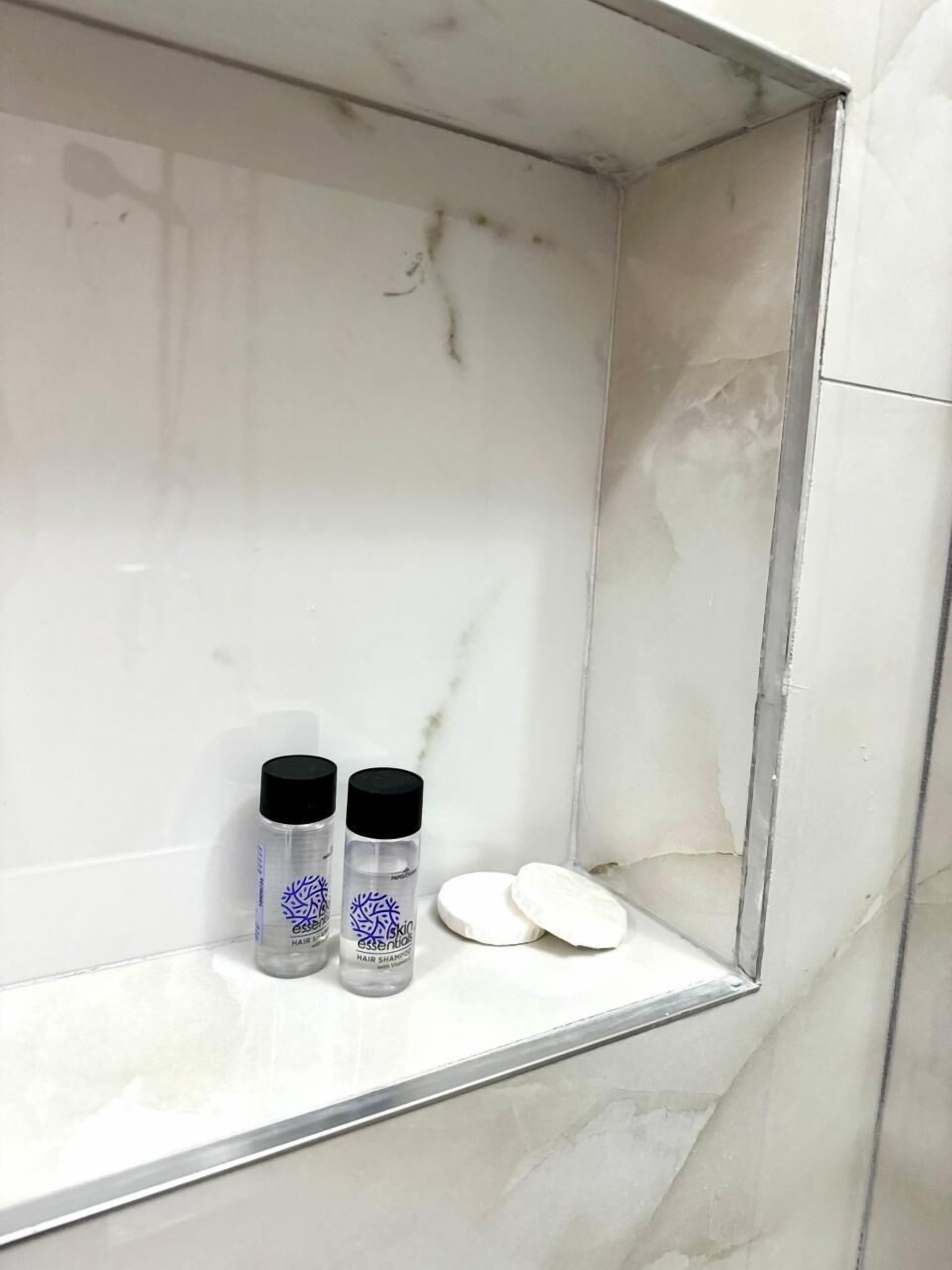 Ein Badezimmer mit Waschtisch aus Marmor, zwei Haarschampoos und zwei weißen Seifenstücken.