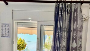 Ein Schlafzimmer mit einem Bett, einem Fenster mit Blick auf Grünflächen und einem Vorhang.