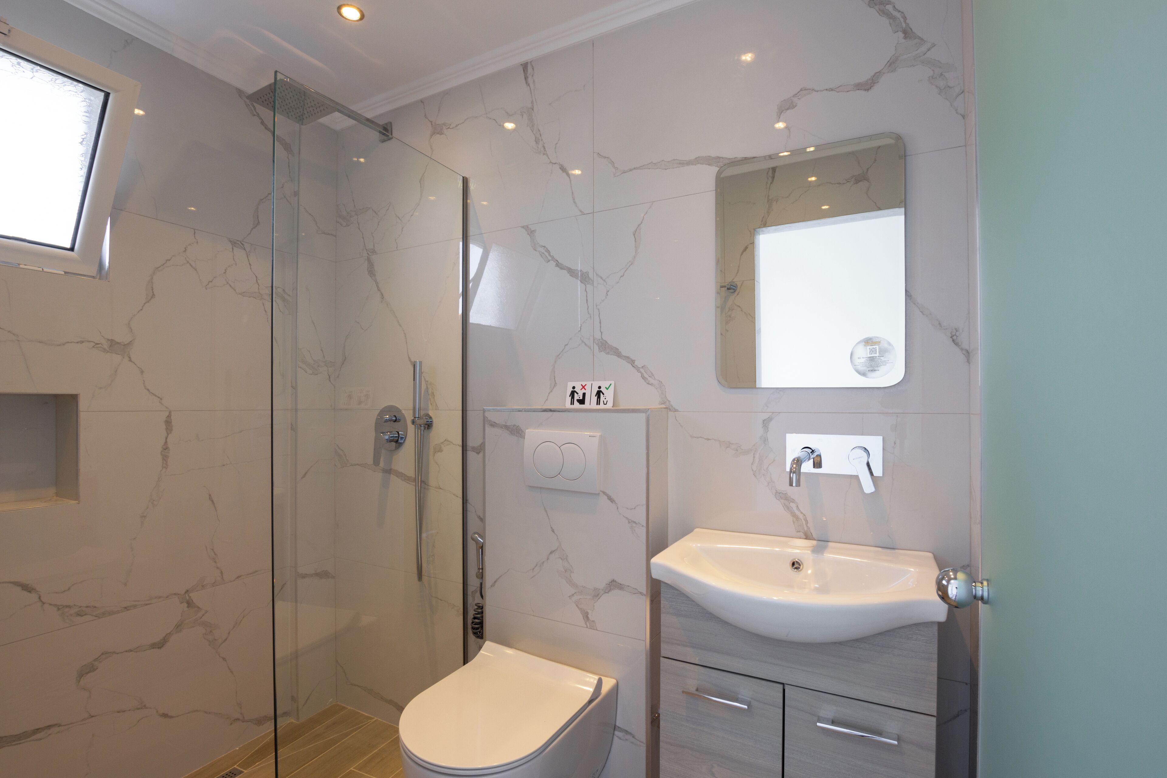 A bathroom with a glass-enclosed shower, a toilet, a sink, and a mirror.