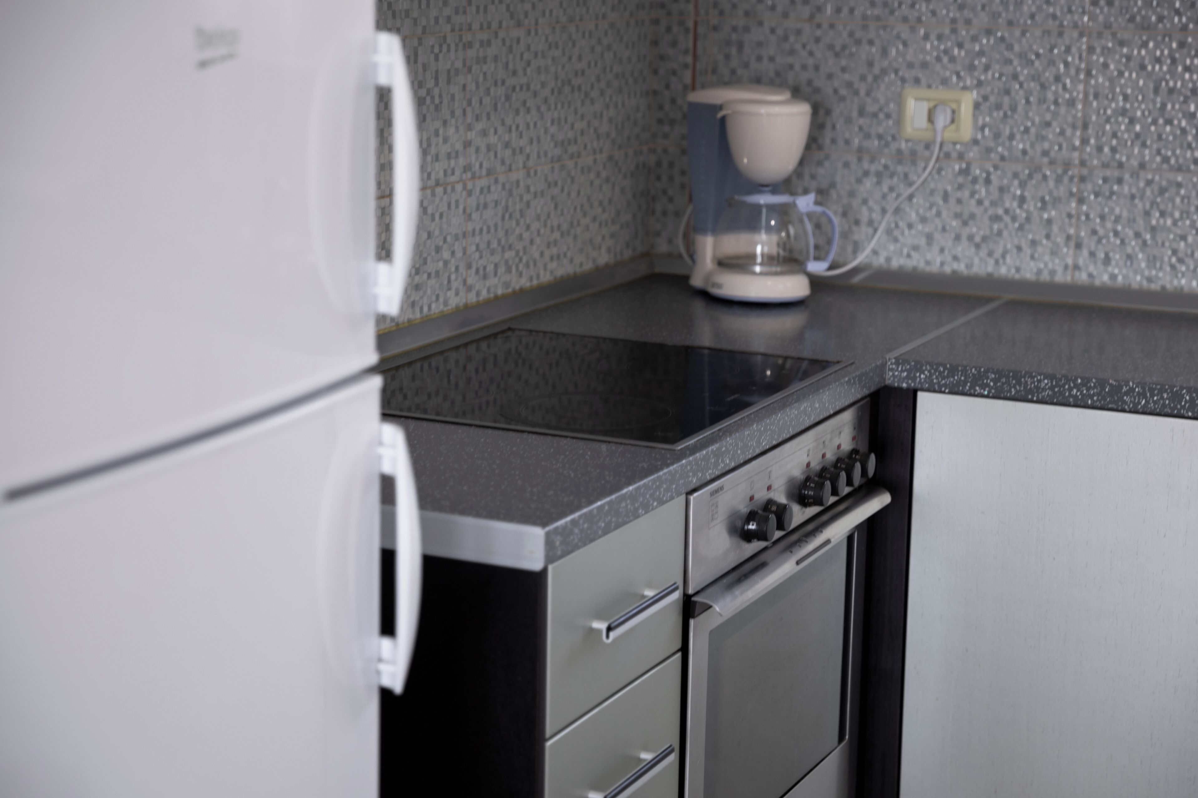 A kitchen with a stove, oven, and coffee maker.