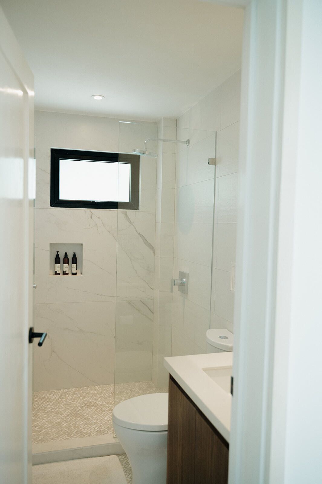 Une salle de bain moderne équipée d’une douche, de toilettes et d’un meuble-lavabo avec un miroir.