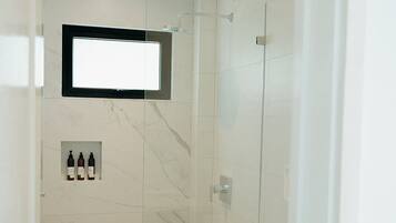 Une salle de bain moderne équipée d’une douche, de toilettes et d’un meuble-lavabo avec un miroir.