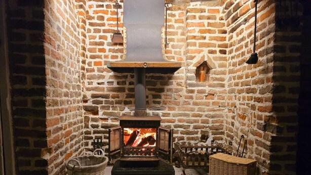A cozy room with a brick fireplace, a wooden bench, and a basket. - Beautiful historic cottage pets welcome (Birchington-on-Sea)