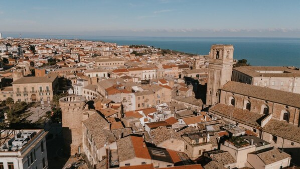 A coastal cityscape with historic buildings, a prominent tower, and a view of the sea.