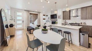 A modern kitchen with a central island, wooden cabinets, and a stainless steel range hood. - Modern Congress Park Retreat (Denver)