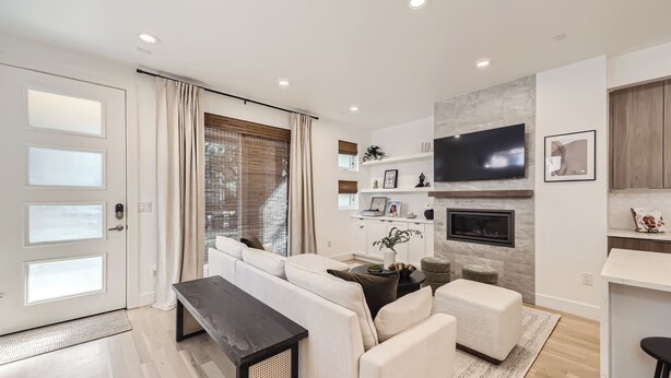 A modern living room with a sofa, a coffee table, and a TV mounted on the wall. - Modern Congress Park Retreat (Denver)