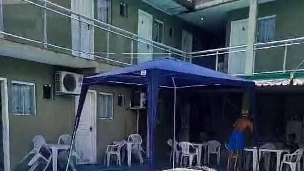 Un espace piscine comprenant deux piscines, un espace de repos couvert et un bâtiment en arrière-plan.