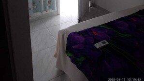 Une chambre à coucher avec un lit, une porte donnant sur un balcon et une vue sur l’extérieur.