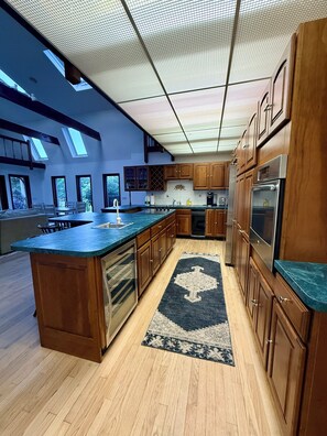 A modern kitchen with wooden cabinets, a central island, and skylights.