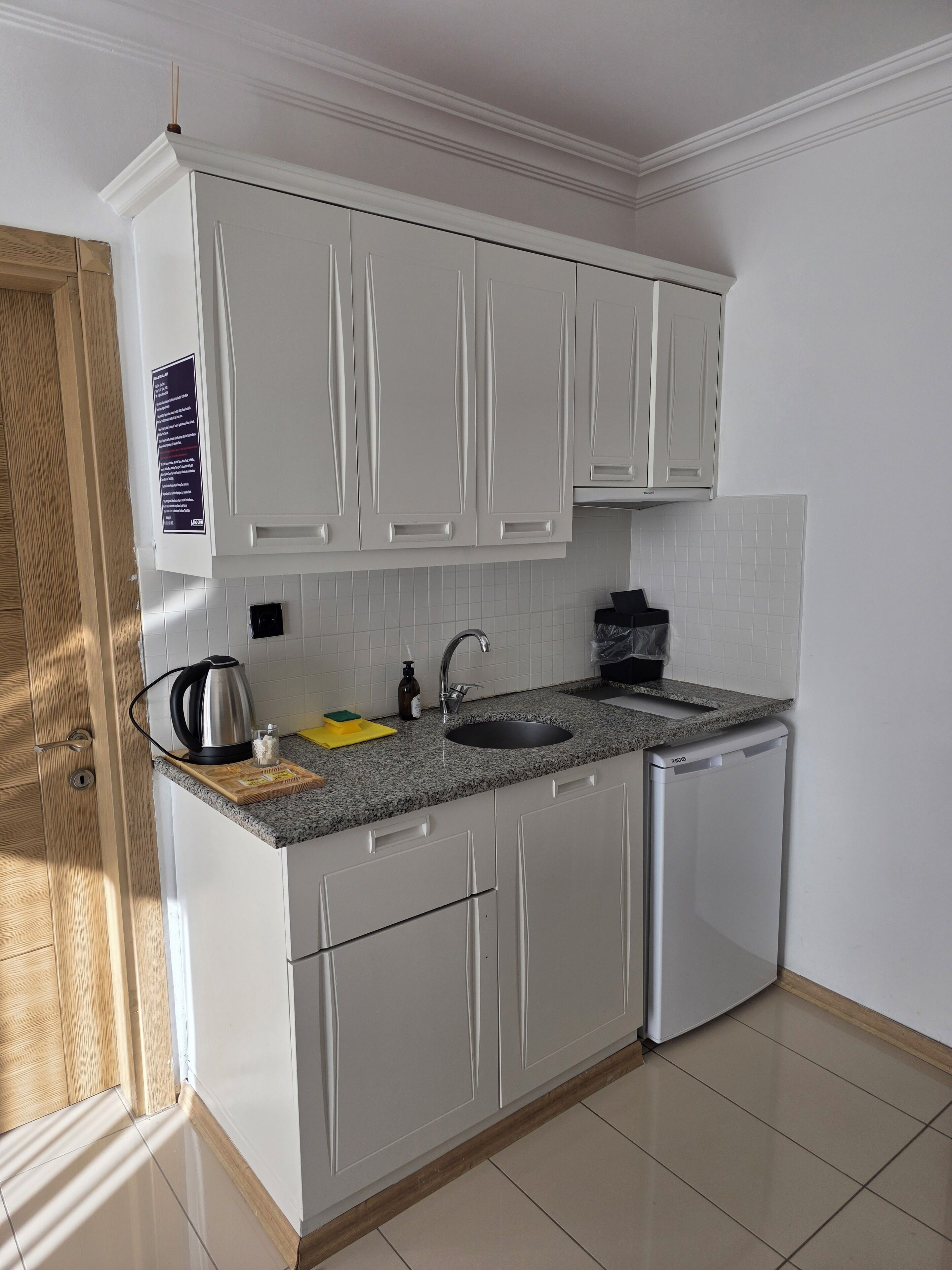 A modern kitchen with white cabinets, a granite countertop, a built-in sink, and a dishwasher.