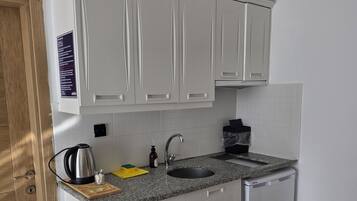 A modern kitchen with white cabinets, a granite countertop, a built-in sink, and a dishwasher.