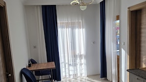 Una cocina moderna con encimera y armarios de madera, un comedor con mesa y sillas, y una alfombra estampada en el suelo.