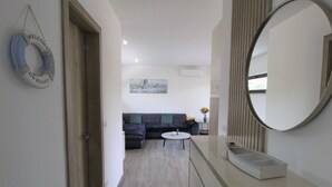 A modern living room with a dark-colored sofa, a small round coffee table, and a large mirror. - Modern semi-detached house, quiet location, 6 minutes to the coast. (Bašanija)