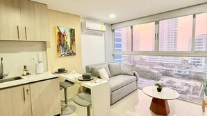 Un appartement moderne doté d’une cuisine, d’un coin repas et d’une grande fenêtre offrant une vue sur la ville.