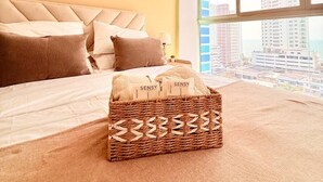 Une chambre à coucher avec un lit, des oreillers, une table de chevet et une vue sur les bâtiments par la fenêtre.