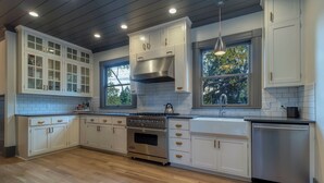 Una cucina moderna con mobili bianchi, un piano cottura in acciaio inossidabile e una lavastoviglie.