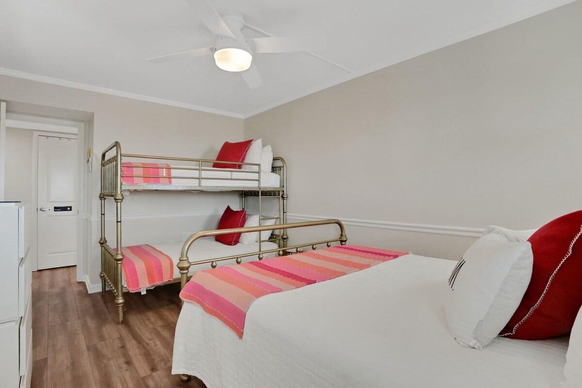 A room with two bunk beds, a ceiling fan, and a white door.