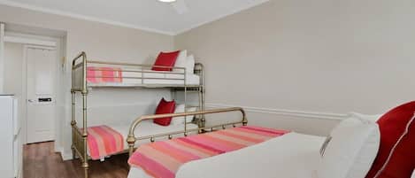 A room with two bunk beds, a ceiling fan, and a white door.