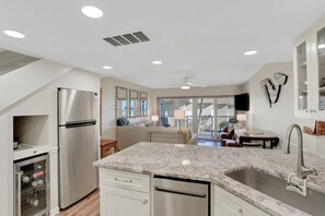 A modern kitchen with a stainless steel refrigerator, a built-in dishwasher, and a granite countertop.