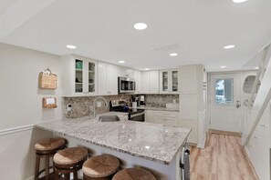 A kitchen with white cabinets, a granite countertop, and a built-in oven.