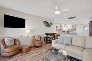 Un salon moderne comprenant un canapé, deux fauteuils, une table basse et un coin repas avec une table et des chaises.
